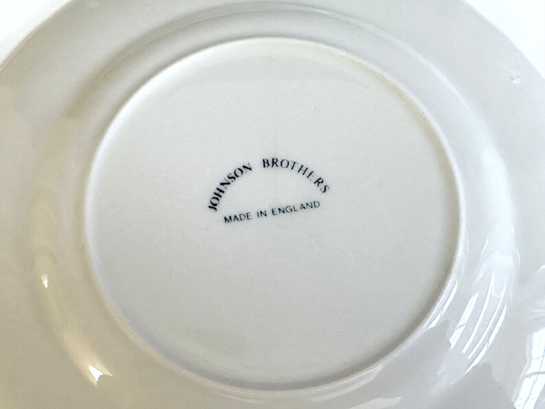 May include: White ceramic plate with a black inscription that reads "Johnson Brothers Made in England".