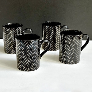 May include: Set of four black ceramic mugs with gold herringbone pattern.