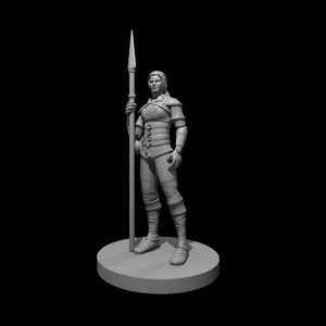 May include: A gray 3D printed miniature of a female figure holding a spear. The figure is wearing armor and is standing on a round base.
