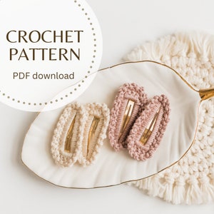May include: Crochet pattern PDF download for making hair clips. Two pairs of hair clips are shown, one pair is beige and the other is pink.