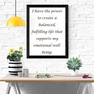 Op de afbeelding: Een zwart gelijst motiverend citaat op een witte bakstenen muur. De quote luidt: "Ik heb de kracht om een ​​gebalanceerd, vervullend leven te creëren dat mijn emotionele welzijn ondersteunt."