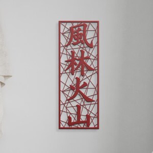 May include: A rectangular, red wall art piece with Japanese characters. The characters are 風林火山, meaning Wind, Forest, Fire, Mountain. The art piece has a geometric, open design, with the characters cut out of the red material.