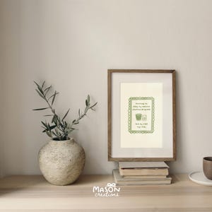 May include: A framed print with a green illustration of a glass of water and a small jar. The text reads "Ditching to stay my matcha green smoothie habit and my vibe tap-ti-tap".