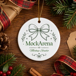 May include: A round white ceramic ornament featuring a dark green line art illustration of a bow at the top, with the text MockArena and Mockup Studio printed in the centre, suspended by a thin gold string for hanging on a holiday tree.
