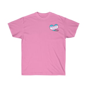 May include: Pink t-shirt with a transgender pride heart and the word "POTATE" inside the heart.