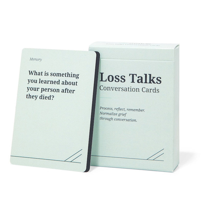 May include: A set of conversation cards called "Loss Talks" with a light blue background and black text. The card shown has the text "What is something you learned about your person after they died?" and the category "Memory".