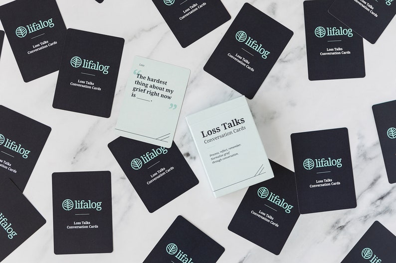 May include: A set of black and white conversation cards with the text "Loss Talks Conversation Cards" and a green leaf logo. The cards are designed to help people process, reflect, remember, and communicate grief through conversation.