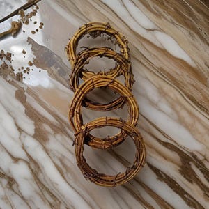 Può includere: Quattro ghirlande di ramoscelli marroni impilate l'una sull'altra su una superficie di marmo.