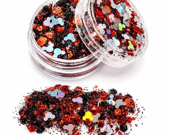 May include: A clear plastic cosmetic jar filled with a mixture of red, black, and orange glitter, featuring iridescent, holographic mouse-shaped sequins. A small pile of the same glitter mixture is spread out in front of the open container.