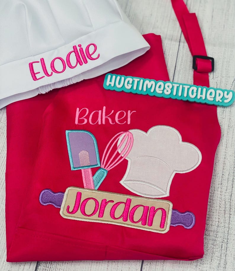 May include: A bright pink apron and a white chef hat. The hat features the embroidered name Elodie in pink. The apron displays the text Baker, a purple spatula, a pink whisk, a white chef hat, and the name Jordan in pink on a rolling pin.