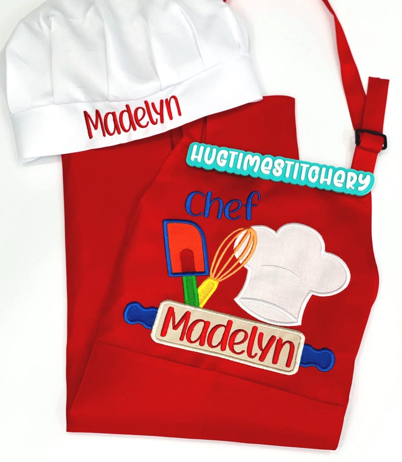 May include: A red apron and white chef hat set featuring embroidered kitchen tools, a rolling pin, and the name Madelyn in red and blue thread. The apron includes the text Chef and HUGTIMESTITCHERY, while the hat displays the name Madelyn.