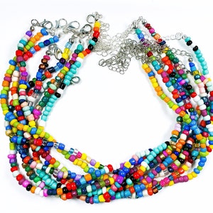 Puede incluir: Un conjunto de collares de cuentas de colores con cierres plateados. Los collares están hechos de pequeñas cuentas redondas en una variedad de colores, incluyendo rojo, naranja, amarillo, verde, azul, morado y rosa.