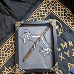 May include: A framed display featuring a brown and black segmented worm, a white skeletal bat, and a black background. The frame has ornate gold corners.