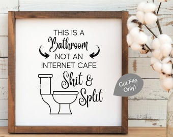 May include: A framed wooden sign with the text "THIS IS A Bathroom NOT AN INTERNET CAFE Shit & Split" in black lettering. A toilet graphic is below the text. A mason jar with cotton stems is to the right.