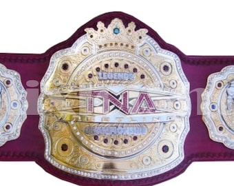 May include: A gold and red wrestling championship belt with the words "Legends" and "TNA" on the center plate. The belt has a crown on top and two side plates with a wrestler's silhouette.