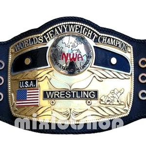 Könnte beinhalten: Ein gold-schwarzer Wrestling-Championschaftsgürtel mit den Worten "Worlds Heavyweight Champion" und "NWA Wrestling Alliance" darauf. Der Gürtel hat ein schwarzes Lederband mit goldenen Akzenten und eine große, vergoldete Mittelplatte mit einem Globus und den Worten "U.S.A." und "Wrestling" darauf.