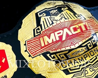 May include: A gold and black wrestling championship belt with the text "IMPACT! Wrestling World Champion". The belt has a large central plate with red and gold accents and a black leather strap.
