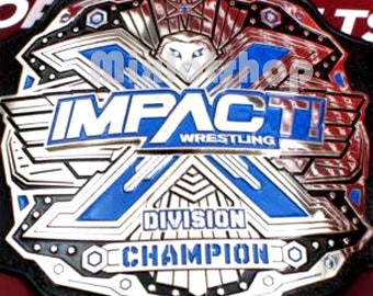 May include: A silver and blue wrestling championship belt with the words "IMPACT! WRESTLING" and "DIVISION CHAMPION" on it.