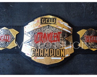 Op de afbeelding: Een gouden en zwarte worstelkampioensgordel met de woorden "Ultraviolent Champion" en "GCW" erop.