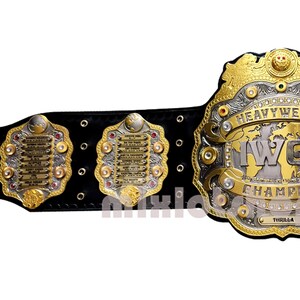 May include: A gold and silver championship belt with a black leather strap. The belt features a large, ornate centre plate with the words "Heavyweight Champion" and "IWC" in silver lettering. The belt also has three smaller plates with lists of past champions.