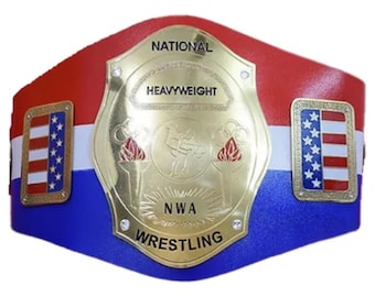 May include: A gold championship belt with a red, white, and blue strap. The belt features a large gold plate with the words "National Heavyweight NWA Wrestling" and a graphic of a wrestler. The belt also has two small American flag patches.