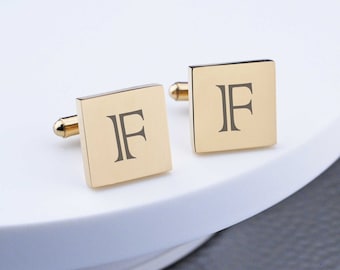 May include: A pair of gold-toned cufflinks with the letter "F" engraved on each square-shaped cufflink.