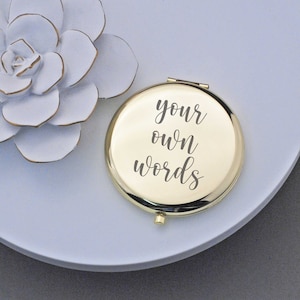 May include: A gold compact mirror with the words "your own words" engraved on the front.