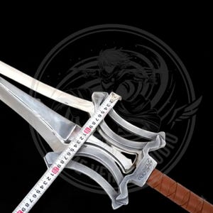 May include: A silver-colored sword with a brown leather-wrapped handle. A measuring tape shows the sword's width. The sword has a decorative hilt and a double-edged blade. The background is black with a graphic design.