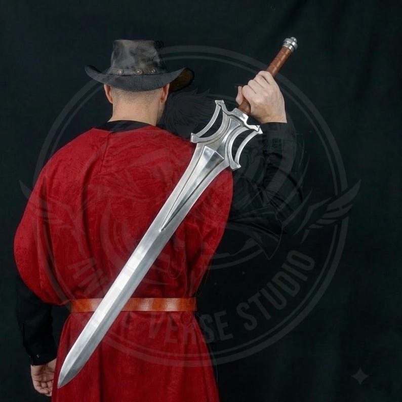 May include: A large, silver sword with a decorative hilt and a brown leather-wrapped handle. The sword is held by a person wearing a red robe and a brown leather belt. The background is dark.