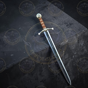 May include: A silver and brown sword with a cross-shaped hilt and a leather-wrapped handle. The sword has a long, straight blade and a decorative pommel. The blade has text on it. The sword is displayed on a dark surface.