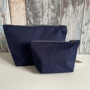 May include: Two navy blue zippered pouches, one larger than the other, on a white surface.