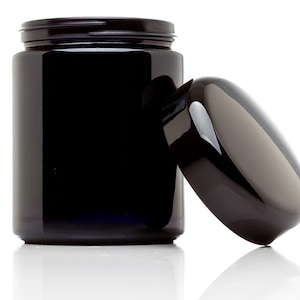 May include: A black glass jar with a black lid. The lid is off and the jar is empty.