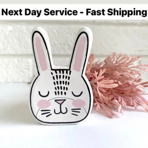 May include: White ceramic bunny figurine with black and pink details. The bunny has closed eyes and a cute, smiling expression.