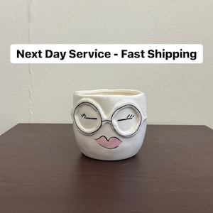 May include: White ceramic planter with a face design. The planter features black-outlined glasses, closed eyes, and pink lips. The text "Next Day Service - Fast Shipping" is displayed above the planter.