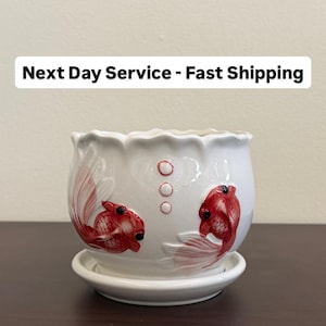 May include: White ceramic planter with a scalloped rim and a matching saucer. The planter is decorated with two red koi fish and three small circles. The text "Next Day Service - Fast Shipping" is at the top.
