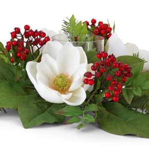 May include: A white magnolia flower centerpiece with red berries and green leaves. The centerpiece includes a clear glass votive holder.