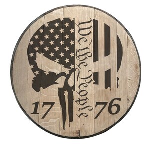 May include: A wooden round sign with a brown skull and crossbones design, an American flag, and the text "We the People 1776".