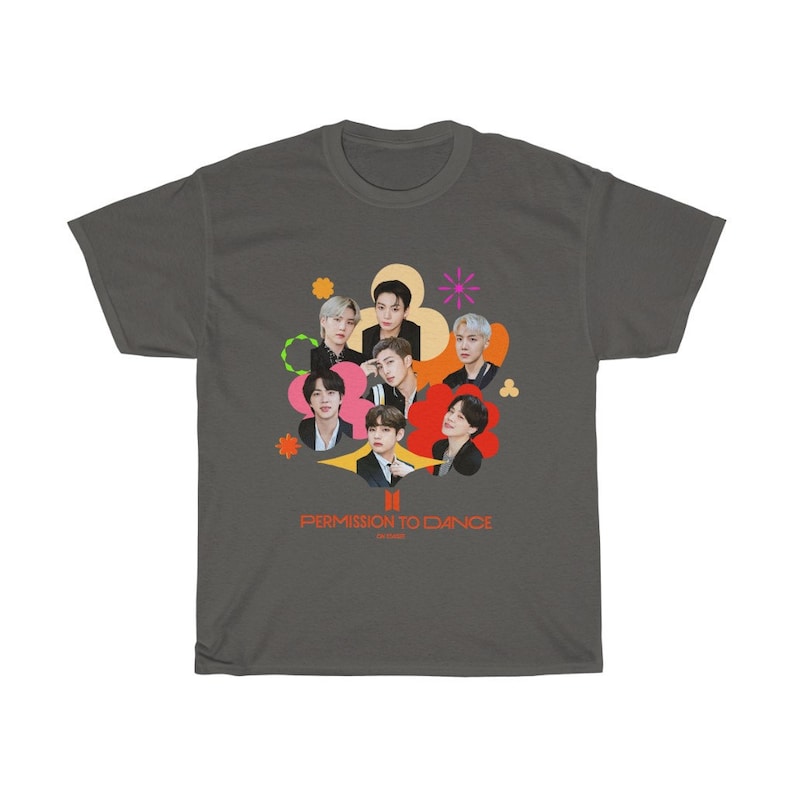 Peut inclure: Un t-shirt gris fonc&eacute; avec un motif color&eacute; de sept hommes dans un design en forme de fleur. Le texte "PERMISSION TO DANCE" est imprim&eacute; sous le graphique.