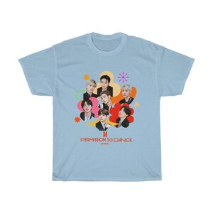 Peut inclure: T-shirt bleu clair avec un graphique color&eacute; de sept personnes en cercle avec le texte "Permission to Dance" en rouge et blanc.