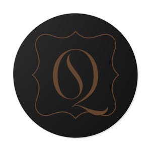 Könnte beinhalten: Ein runder, schwarzer Aufkleber mit einem braunen Buchstaben "Q" in einem dekorativen Rahmen. Der Buchstabe ist in einem stilvollen, fließenden Design gestaltet. Der Kontrast zwischen Braun und Schwarz hebt das Design hervor.