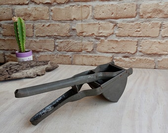 Old metal press, vintage potato press, hand press, food press, primitive mashing tool, retro kitchen.