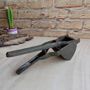 Old metal press, vintage potato press, hand press, food press, primitive mashing tool, retro kitchen.