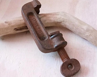 May include: A vintage C-clamp made of rusted brown metal with a threaded screw mechanism and a circular handle. The frame of the clamp features the embossed text OTTO W. RÖBER. The tool has a weathered, oxidised surface texture throughout.