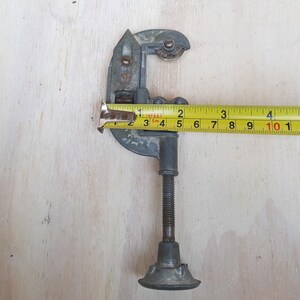 May include: A silver pipe cutter with a black handle and a yellow measuring tape. The tape reads "16 feet" and is marked in inches and centimeters.