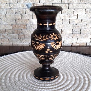 A wooden vase. Vase for dried flowers. Vintage vase. Vase with wood carving. Wood carving of flowers. Home decoration. A wooden vase.