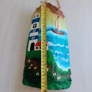 May include: Hand-painted coconut shell art depicting a lighthouse, a small house, a sailboat, and a blue ocean with white clouds. The coconut shell is approximately 30 cm tall.