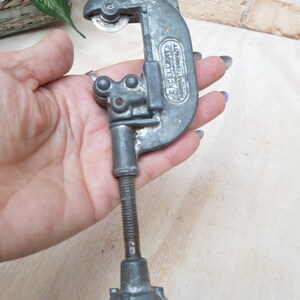 May include: A silver pipe cutter with a black handle and the words "EXCELLENT  IMPROVED QUALITY" printed on the side.