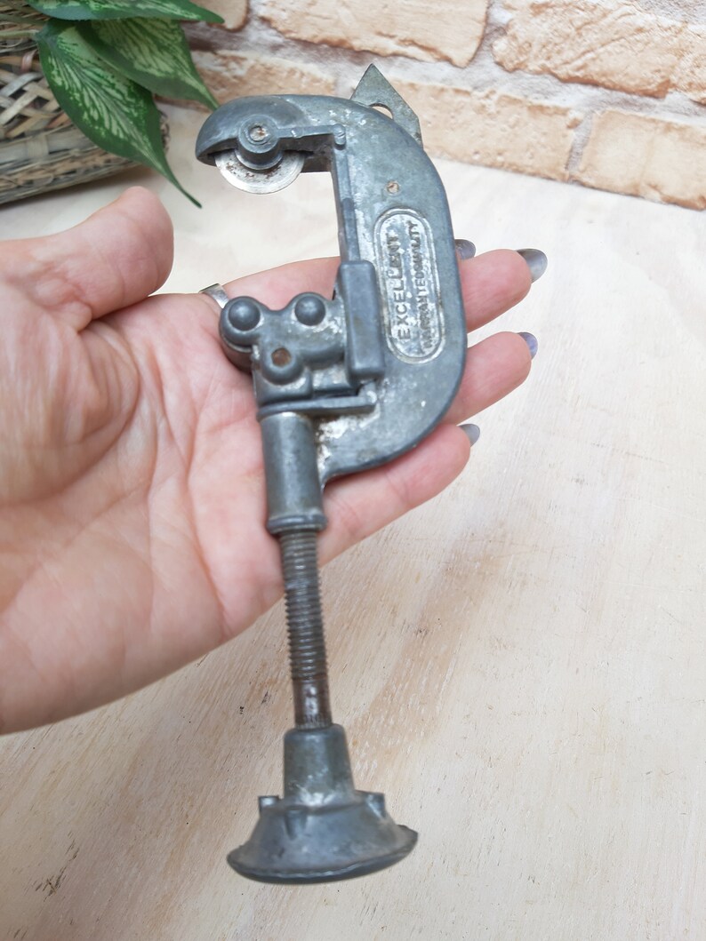 May include: A silver pipe cutter with a black handle and the words "EXCELLENT  IMPROVED QUALITY" printed on the side.