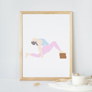 May include: A framed print featuring a minimalist illustration of a person in a yoga pose. The figure is depicted in light blue, pink, and brown tones, with a wooden frame. The artwork is a modern, abstract representation of a yoga practice.