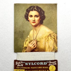 May include: Vintage card advertising "NYLCORD" bead stringing thread. The card features a woman wearing a pearl necklace and a yellow dress. The text reads "British Made NYLCORD" Stronger than Silk for Stringing Pearls and Beads App. 7/2 ins. With Fixed Needle No. 7."